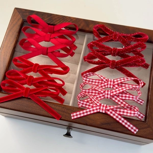 Détail de 12 barrettes nœuds en velours rouge et paillettes dans une boîte en bois