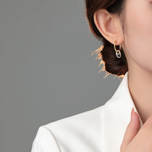 Close-up of gold hoop earrings with silver pig nose charms worn on a female model