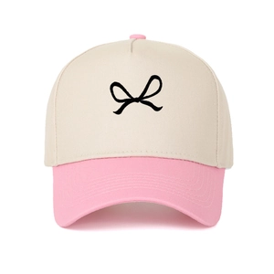 Detailed embroidery of a black bow on a pink and beige color-block baseball cap