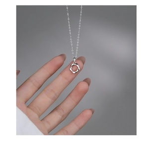 Detailed view of hand holding a silver wave pendant necklace with a minimalist Mobius design