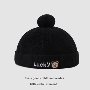 Close-up of black fuzzy kid's hat with Lucky text and bear embroidery detail