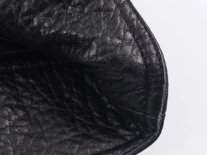 Macro della trama in pelle martellata nera e cuciture di precisione sulla giacca
