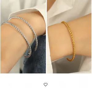 Detailed close-up showing twisted texture on gold and silver open bangle bracelets