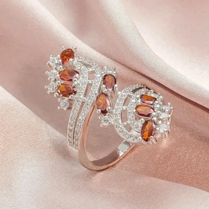 Macro detail of luxury ring with orange amber zircons and pavé diamonds on pink silk