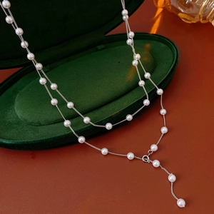 Detail of double-layer silver pearl necklace featuring a Y-shaped drop on green velvet