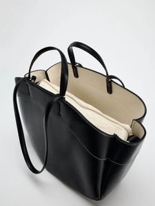 Overhead view showing black leather tote with beige canvas lining and inner pouch