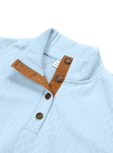 Detail of light blue waffle knit shirt featuring stand collar and brown suede trim