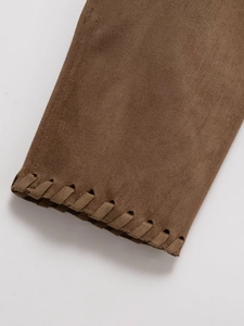 Détail de la veste en daim marron avec bords tissés décoratifs et texture de manche