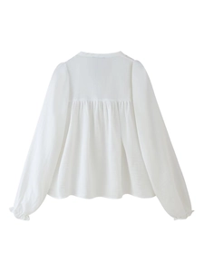 Détail de chemise blanche à manches longues avec corps plissé et poignets à volants
