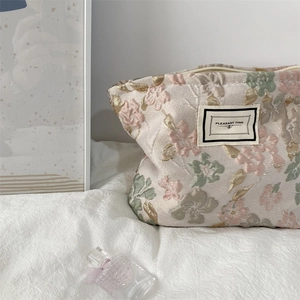 Détail de la trousse de maquillage en jacquard floral avec logo sur textile texturé