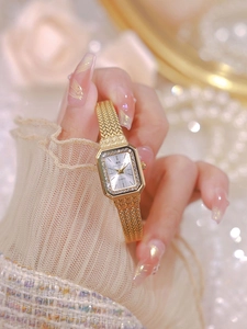 Detailed shot of a gold square watch with rhinestone bezel worn on a woman's wrist