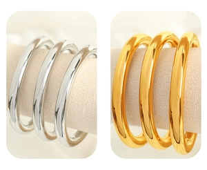 Close-up of polished C-shaped cuff bracelets in gold and silver finish on soft display pads
