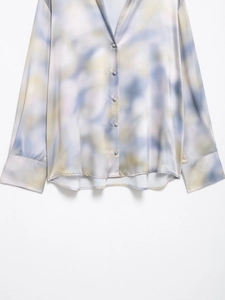 Close-up of elegant tie-dye satin shirt in light blue and yellow with smooth texture