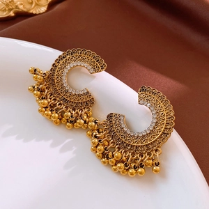 Detail of vintage gold C-shaped earrings with white rhinestones and dangling charms