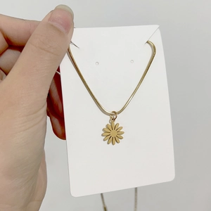 Macro shot of 18K gold daisy pendant necklace featuring a polished snake chain texture