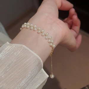 Gros plan du bracelet de perles tissé à double rangée avec chaîne réglable en métal doré
