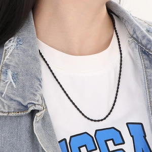 Detail of a black stainless steel rope chain necklace worn on a model's neck