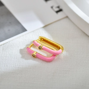 Vue macro de boucles d'oreilles rectangulaires émaillées roses et dorées avec strass