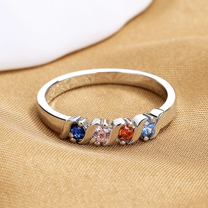 Minimalist silver ring with colorful zircons on gold satin fabric backdrop