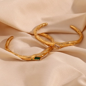 Detail of 18K gold plated open cuff with lava texture and green rectangular zircon