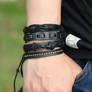 Close-up of 4-piece multilayer black leather bracelets with guitar charms and metal studs