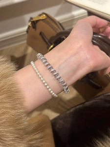 Detail showing a 18K gold plated twisted bracelet with pearls and sparkling zircon accents