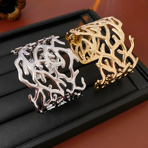 Macro shot of gold and silver coral hollow-out bangles on black leather jewelry tray