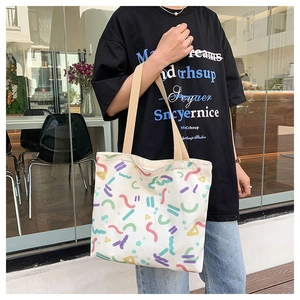 Detail of canvas tote bag with colorful Memphis style abstract patterns and strap
