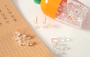 Rose gold push pins in a carrot shaped box on a desk calendar with soft warm lighting