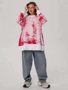 Detail shot of distressed cuffs on oversize gradient knit sweater with red paint splatter