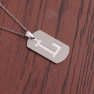 Détail d'un collier en acier inoxydable argenté avec un pendentif évidé de la lettre L