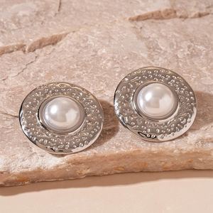 Detail of silver textured hammered metal stud earrings with central white faux pearl