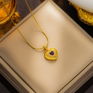 Close-up of gold heart pendant with red emerald-cut stone and zircon halo detail