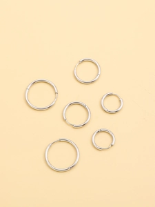 Detailed macro view of six sets of polished silver hoop earrings in varying diameters