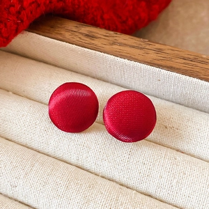 Macro di eleganti orecchini a bottone tondi rossi in una scatola per gioielli beige