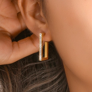 Close-up of gold plated rectangular earrings with white zircon pavé setting on model