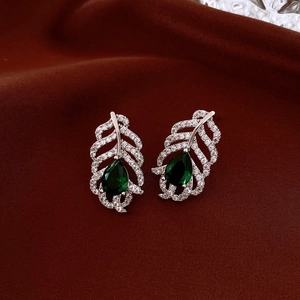 Detail of silver leaf earrings with clear crystals and a green teardrop stone