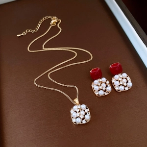 Detail of 18k gold plated necklace and earrings set with pearls and red gemstones