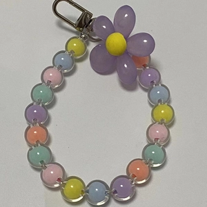 Macro detail of colorful transparent beaded phone strap with resin flower and metal clasp