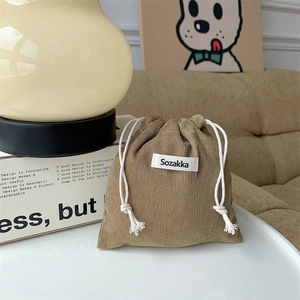 Detailed view of a brown corduroy drawstring bag with Sozakka label on a desk