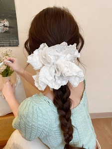 Detailed view of a layered white lace scrunchie styled on a woman's hair in a low bun