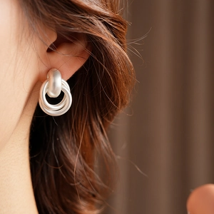 Close-up of matte silver double hoop geometric earrings worn by a model in a minimal style