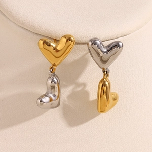 Macro view of gold and silver heart-shaped 316L stainless steel earrings on stand