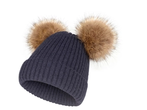 Détail d'un bonnet en tricot bleu foncé avec deux pompons moelleux en fausse fourrure