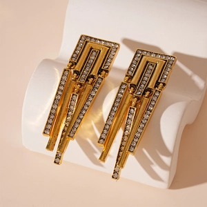 Vintage gold geometric tassel earrings with rhinestones on a textured stone stand