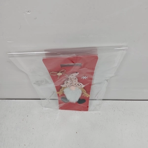 Detail of red gnome wine bottle cover with sequin hat and white beard in packaging