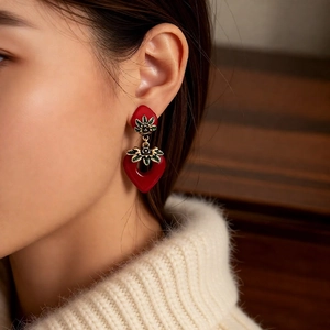 Detail of vintage red enamel heart earrings with green floral accents on model