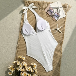 Detail eines weißen Neckholder-Badeanzugs mit Wellenstruktur und Polstern auf Strohmatte