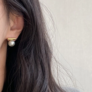 Elegante geometrische Perlenohrstecker mit Goldstab-Detail am Ohr des Models