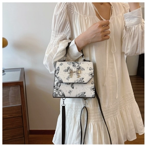 Detailed view of butterfly print handbag with metallic bow on white textured dress
